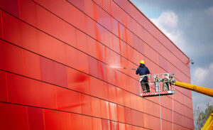 Worker of Professional Facade Cleaning Services washing the red