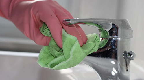Hand putzt Wasserhahn in Badezimmer