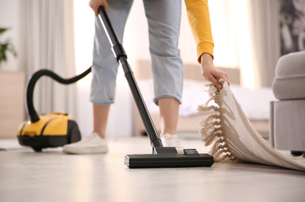 Junge Frau benutzt Staubsauger zu Hause, Nahaufnahme