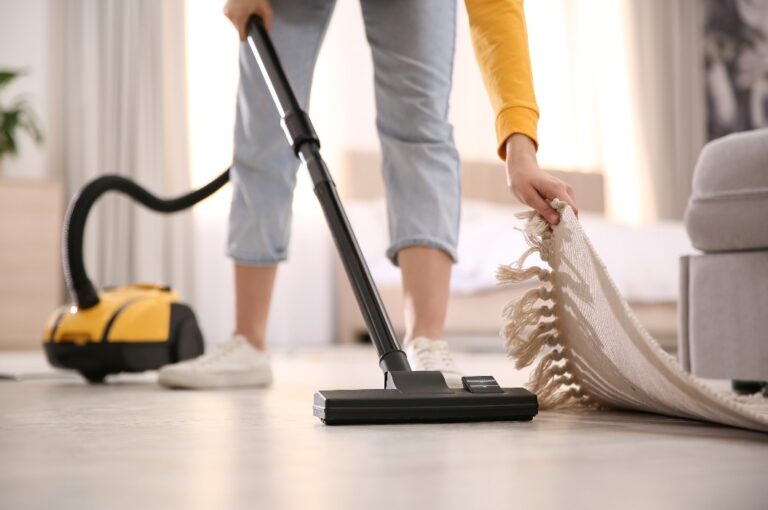 Junge Frau benutzt Staubsauger zu Hause, Nahaufnahme